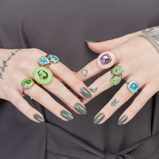 Mão feminina usando o Anel Max Esmaltado Verde banho ouro 18k em composição com outros anéis
