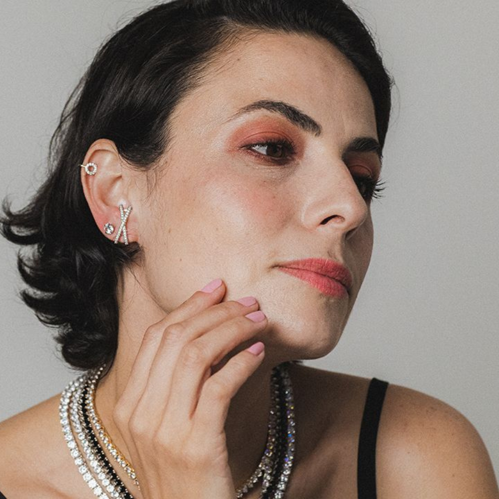 Modelo usando brinco X dourado em look casual contemporâneo