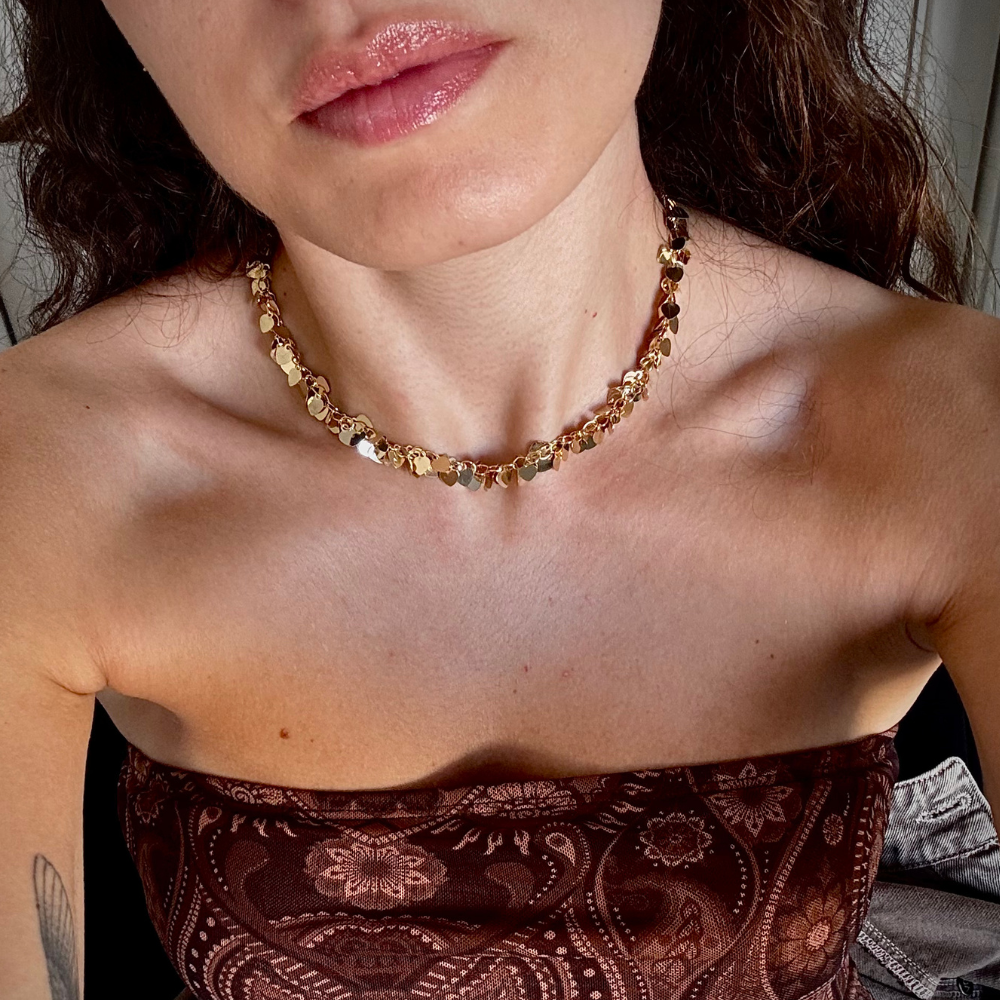 Mulher usando colar pingentes coração dourado no pescoço em look casual