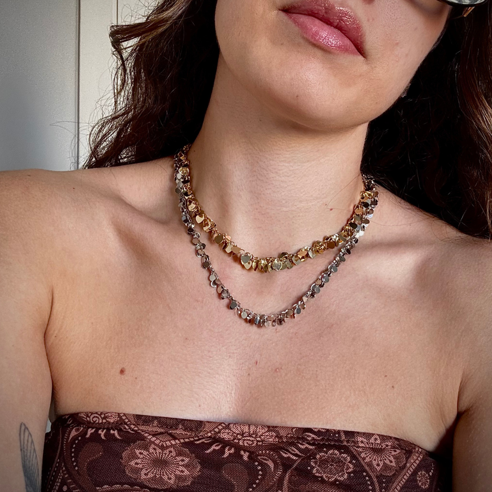 Mulher usando colar pingentes coração dourado no pescoço em look casual