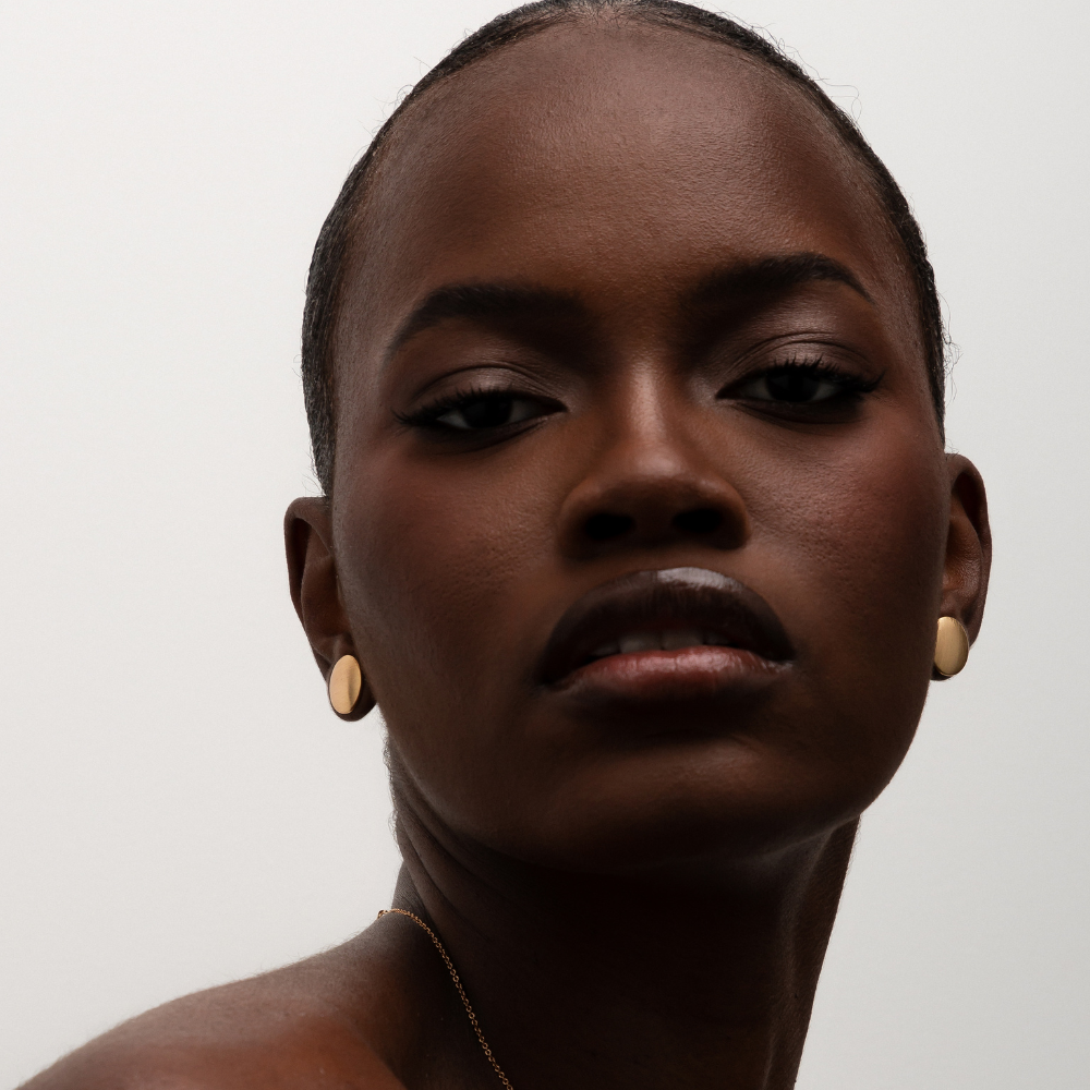 Mulher usando brinco botão dourado ou prateado no dia a dia, visual elegante