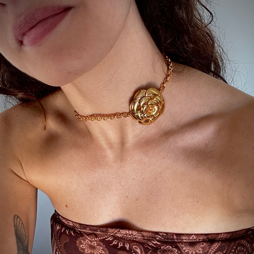 Mulher usando choker flor dourada no pescoço