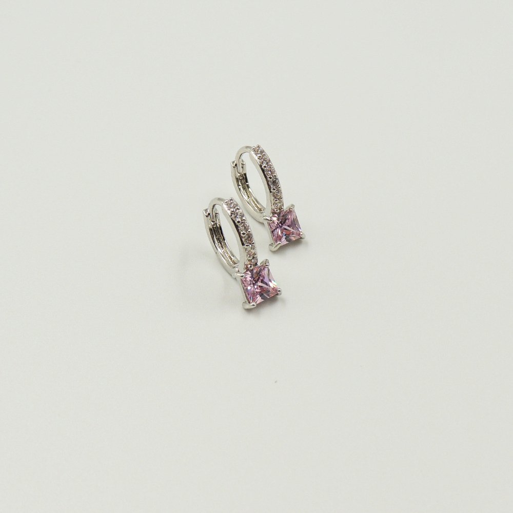 Mulher usando brinco argola prateado com pedra quadrada rosa