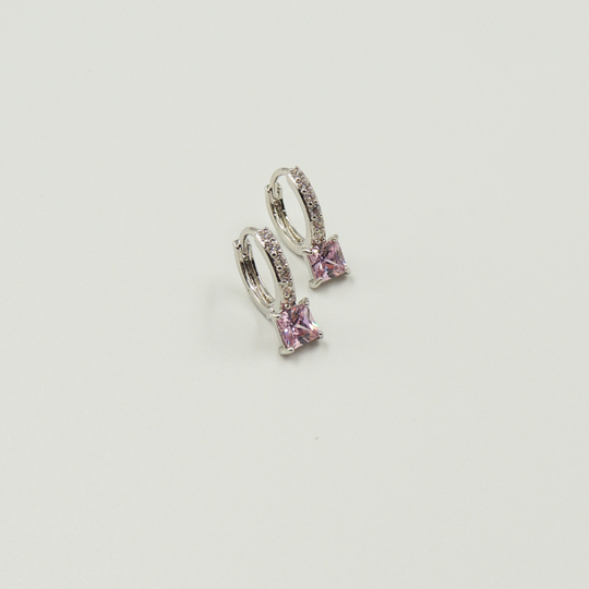 Mulher usando brinco argola prateado com pedra quadrada rosa