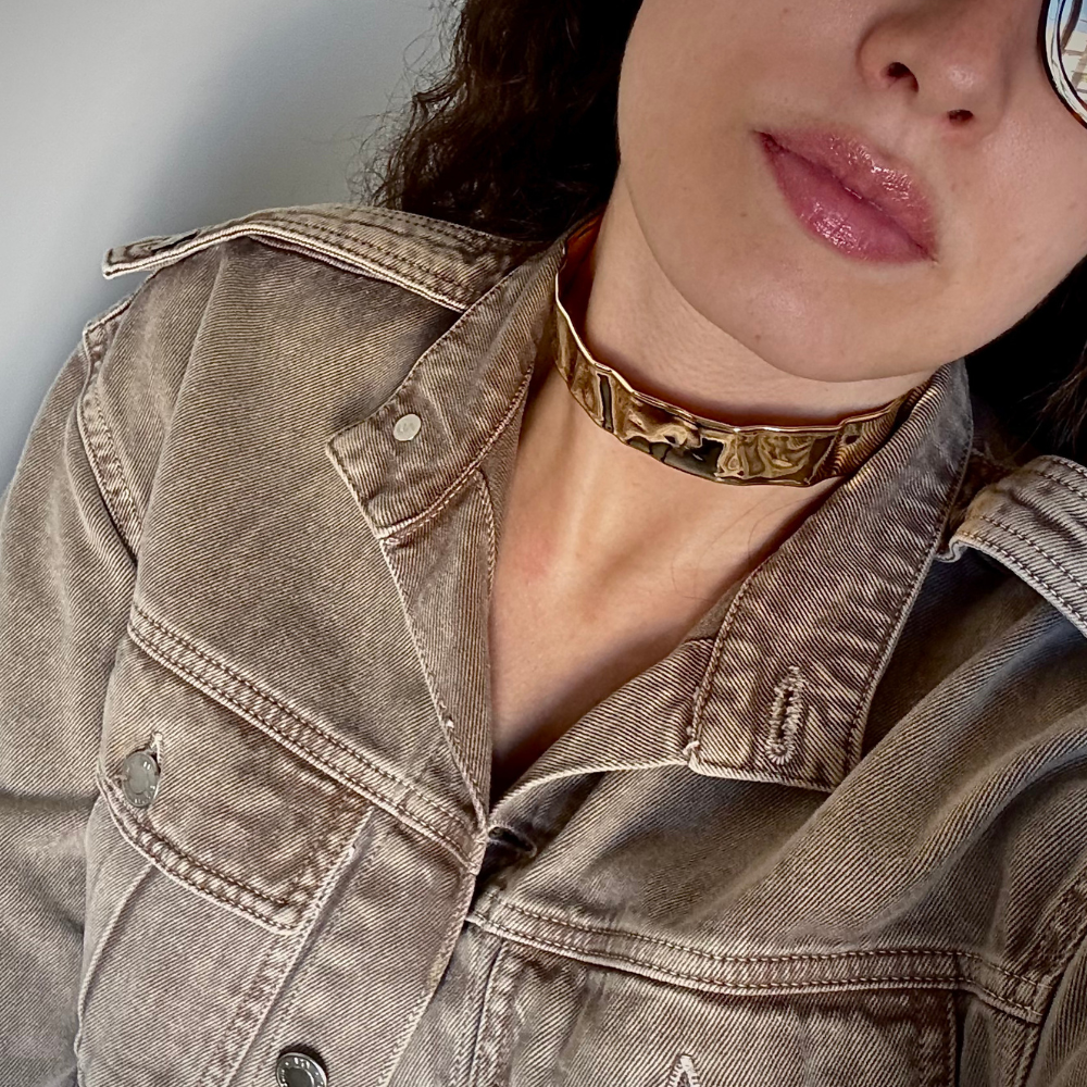 Mulher usando choker rígida martelada dourada com decote elegante