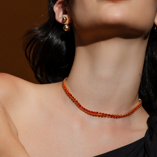 Mulher usando colar riviera laranja banho ouro 18k