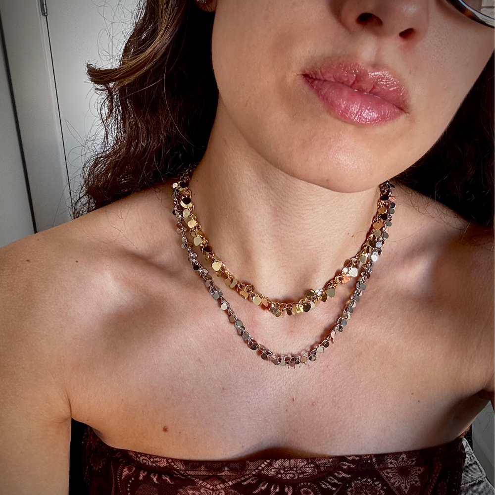Mulher usando colar pingentes coração dourado no pescoço em look casual