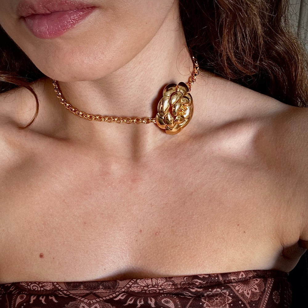 Mulher usando choker flor dourada no pescoço