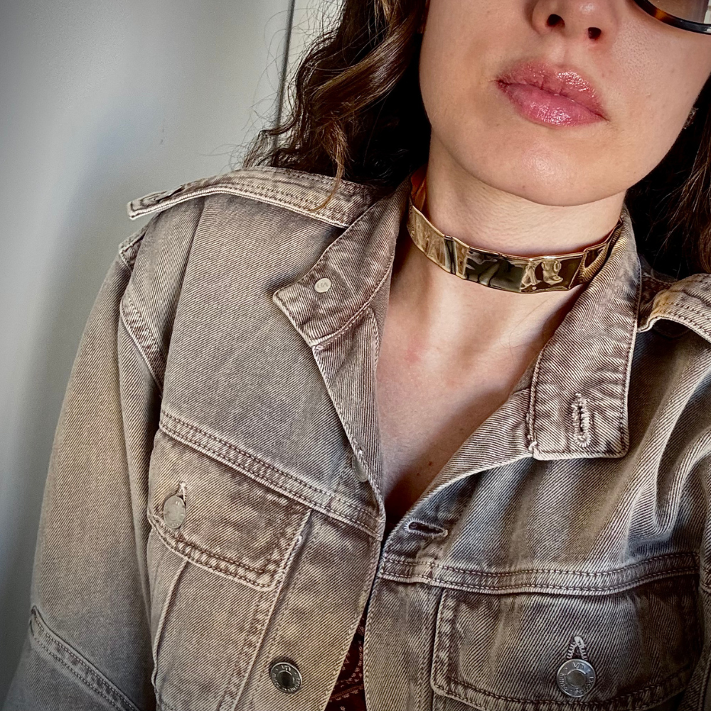 Mulher usando choker rígida martelada dourada com decote elegante