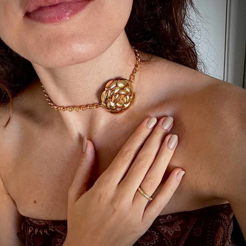 Mulher usando choker flor dourada no pescoço