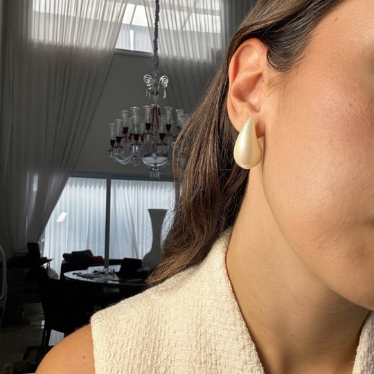Mulher usando brinco gota pérola dourado com pino e tarraxa