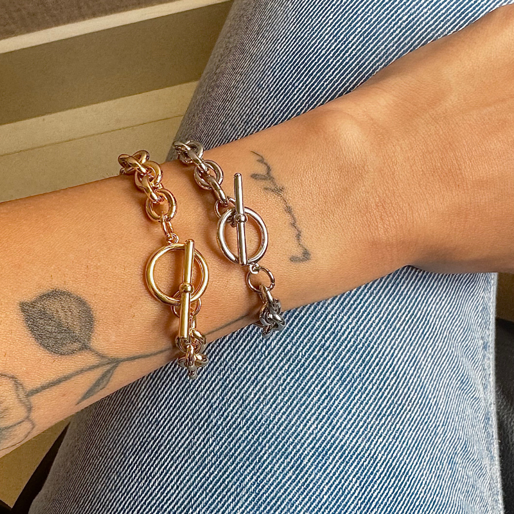 Mulher usando pulseira elos no pulso com outras joias delicadas