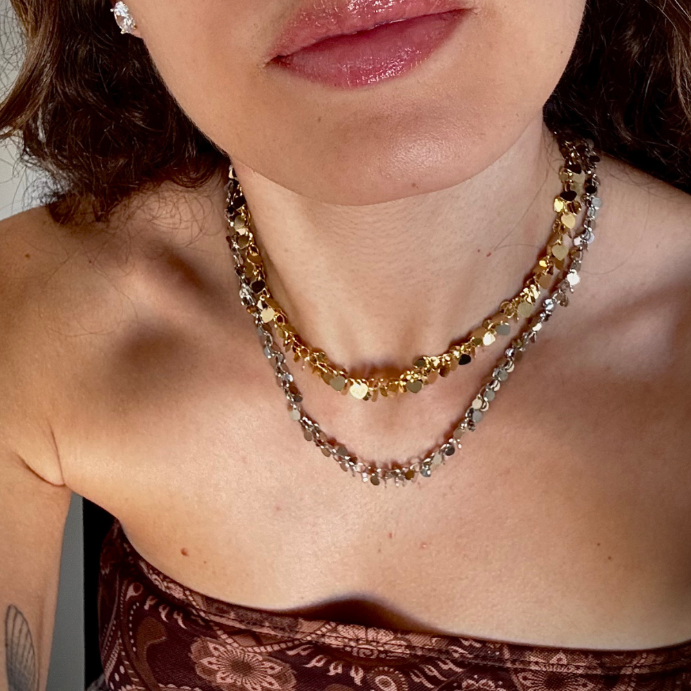 Mulher usando colar pingentes coração dourado no pescoço em look casual