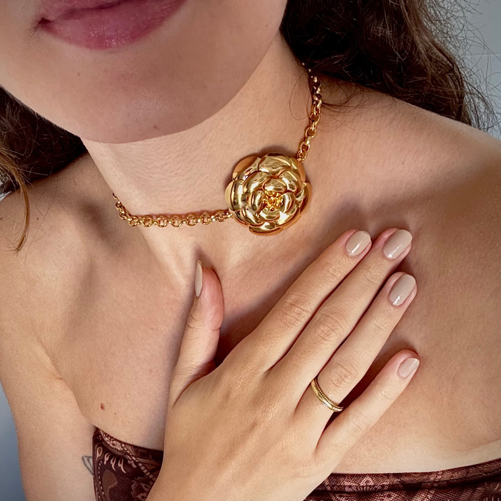 Mulher usando choker flor dourada no pescoço