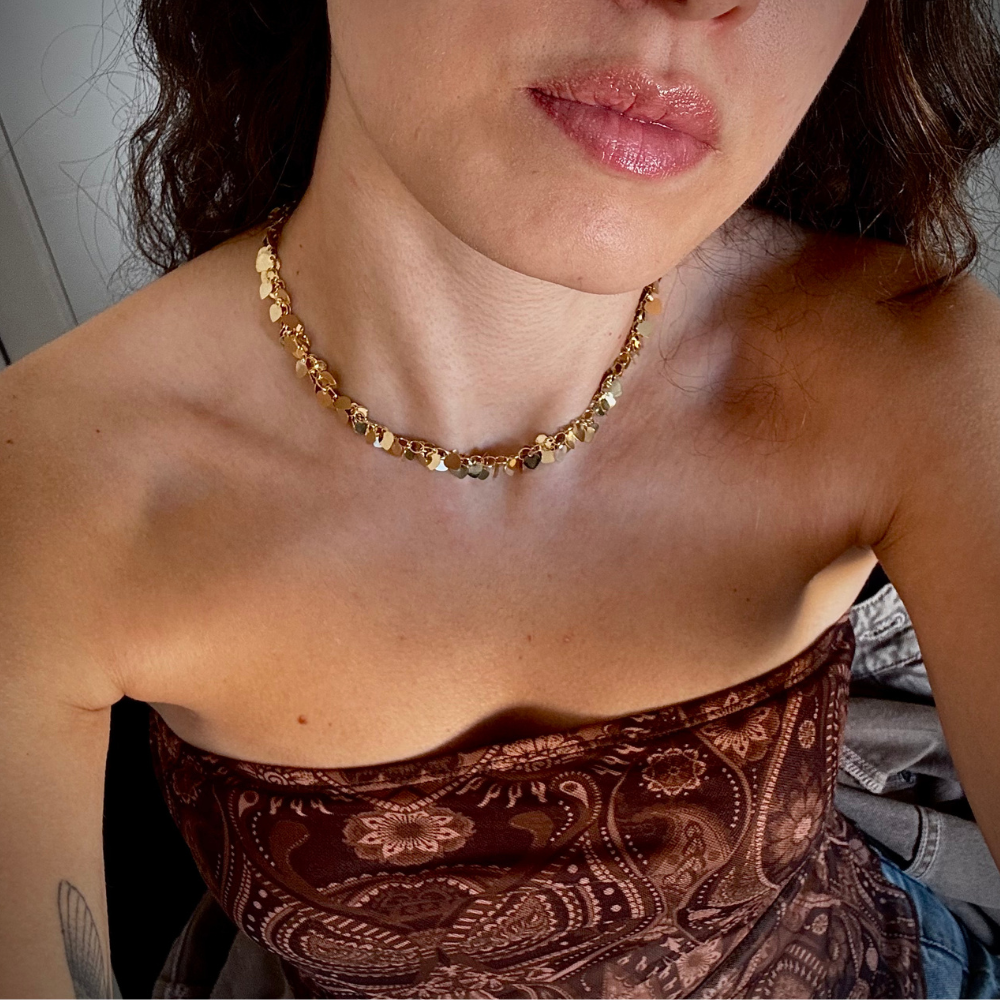 Mulher usando colar pingentes coração dourado no pescoço em look casual