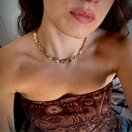 Mulher usando colar pingentes coração dourado no pescoço em look casual