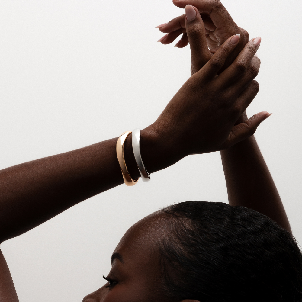 Bracelete curvas dourado usado no pulso em composição elegante