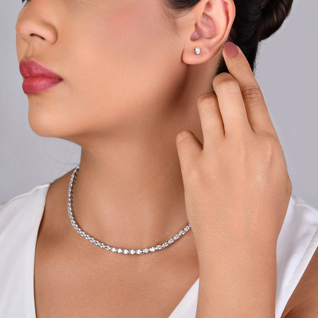 Mulher usando conjunto de brinco e colar prateado com zircônias cristal