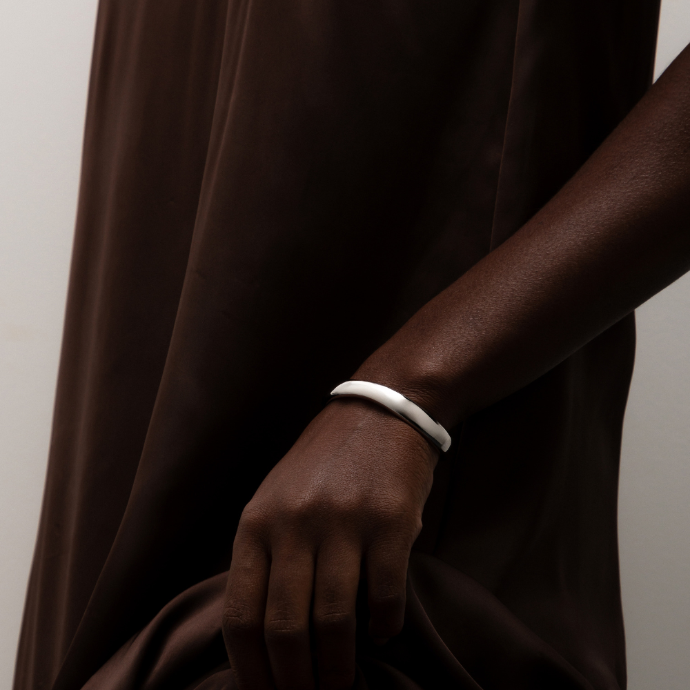 Bracelete curvas dourado usado no pulso em composição elegante