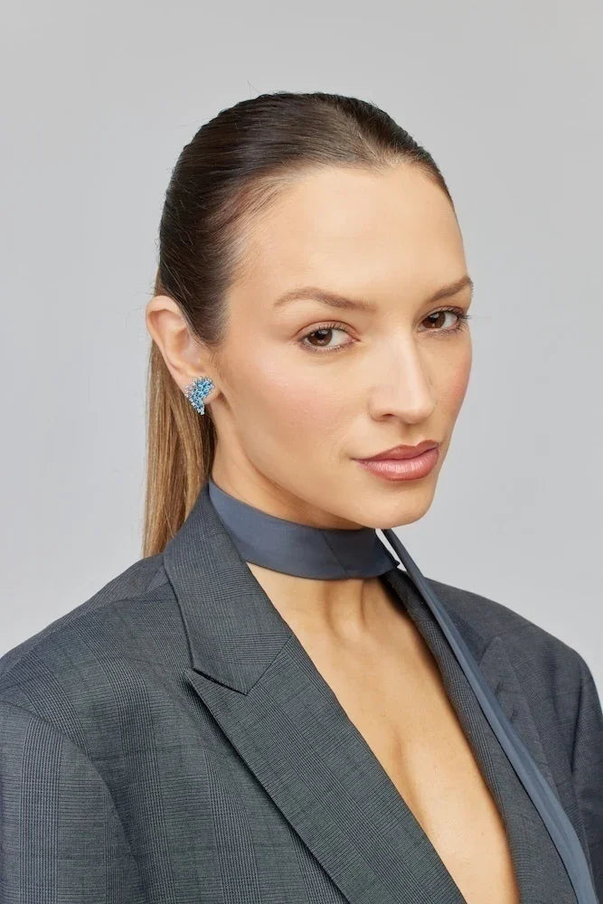 Brinco azul cravejado com detalhes em ouro, usado com blazer cinza e lenço no pescoço